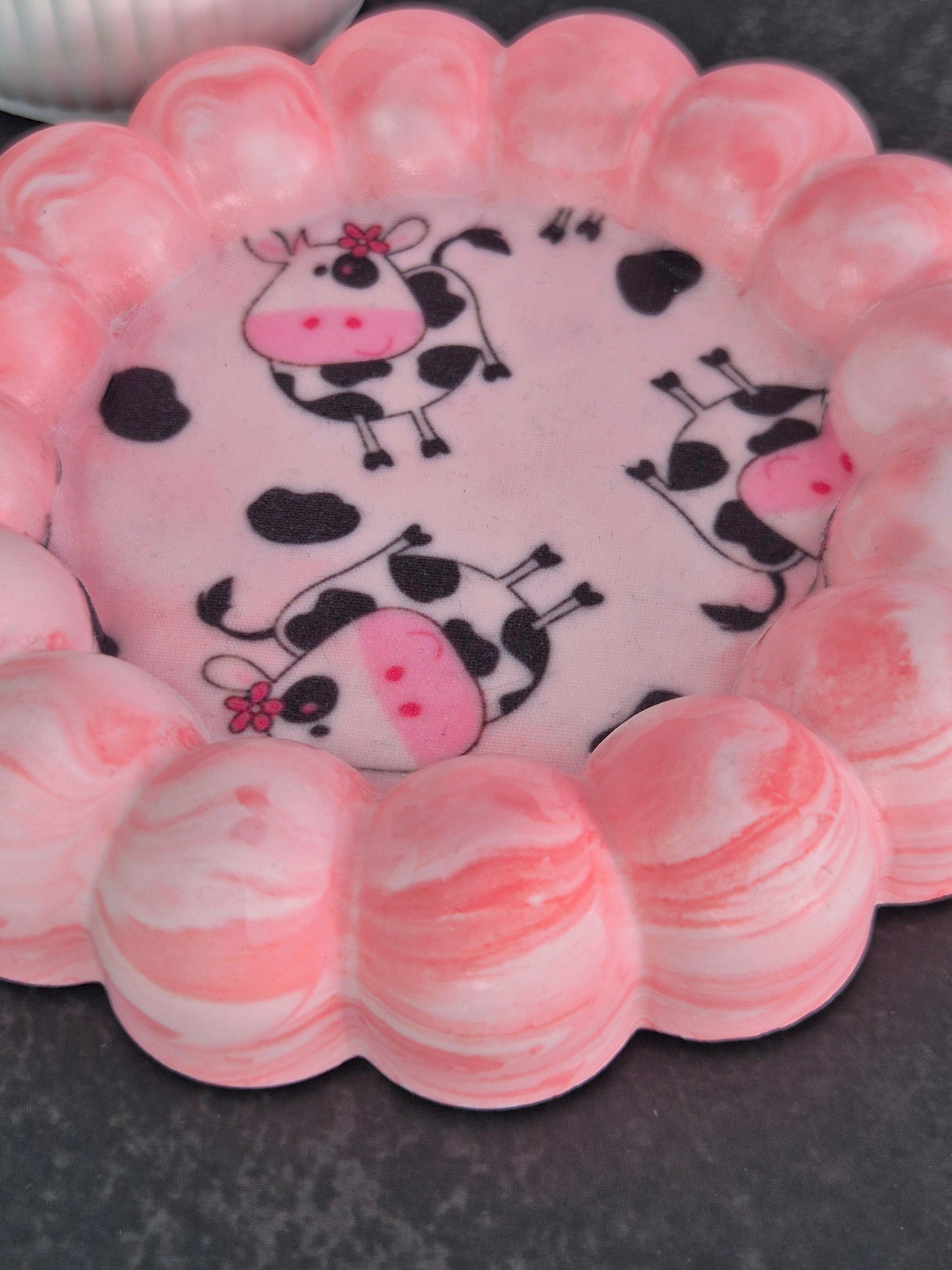 Close-up of a pink cow-print fabric decoupage trinket dish, showing the rounded bubble edge and marbled finish.
