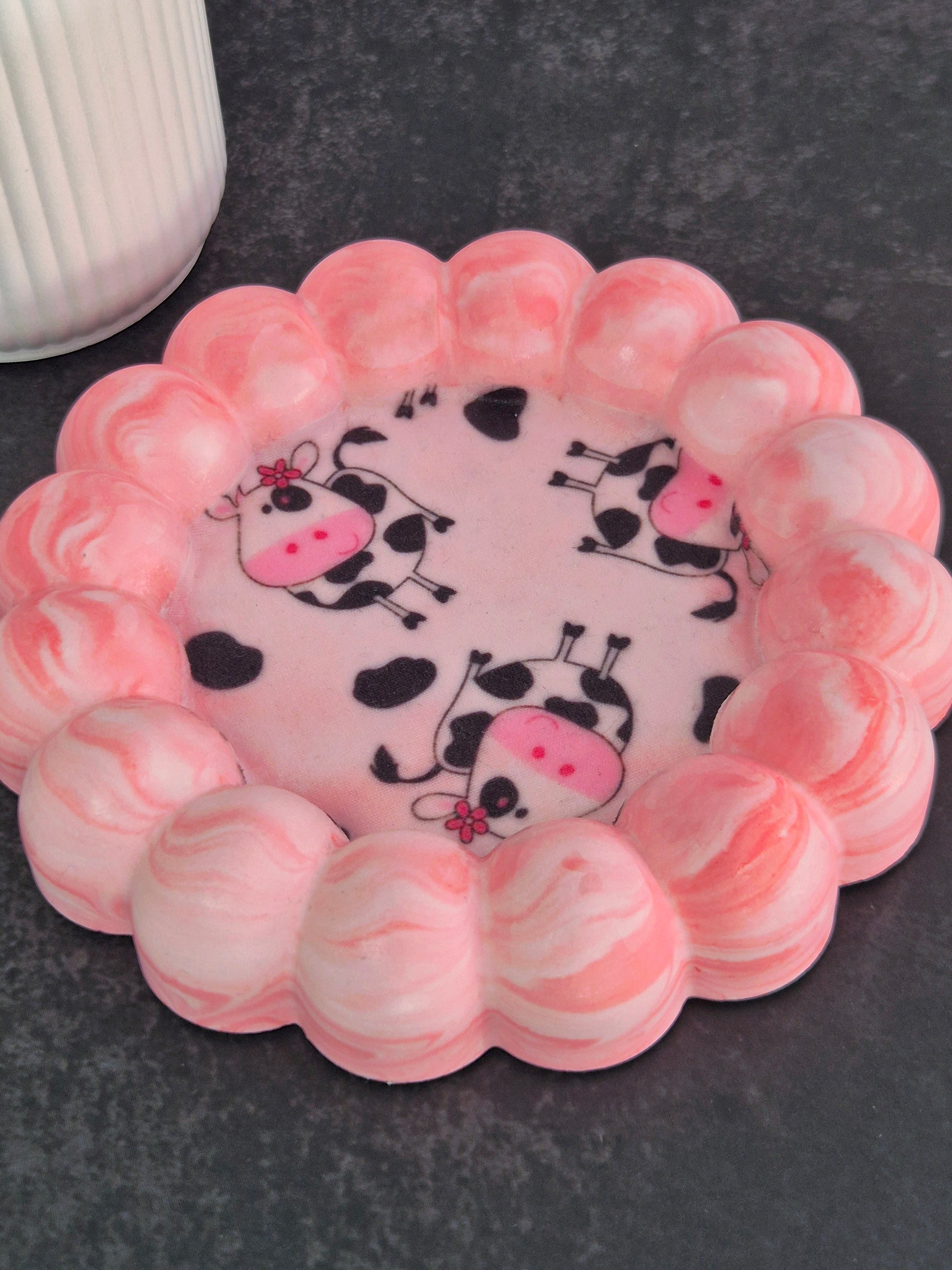Handmade pink and white marbled bubble-edge trinket dish with playful cow-print fabric decoupage in the centre.