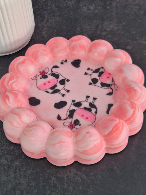 Handmade pink and white marbled bubble-edge trinket dish with playful cow-print fabric decoupage in the centre.