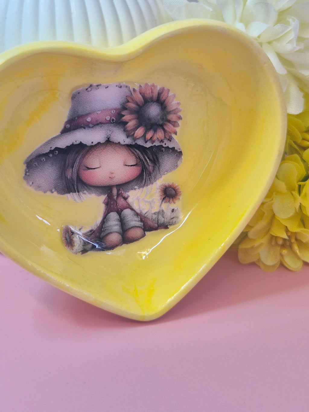 Heart-shaped yellow tri ket dish with a cute girl and sunflowers on a pink surface