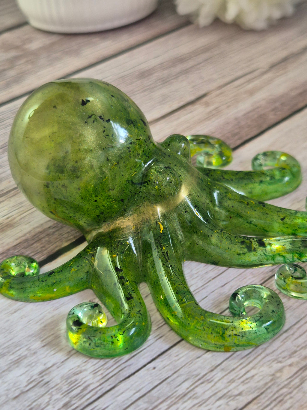 Handmade green resin octopus ornament on a wooden surface side view