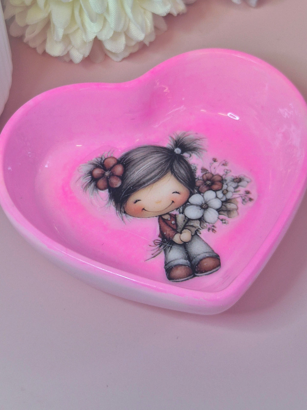 Heart-shaped pink tri ket dish with a girl holding flowers design on a light pink background