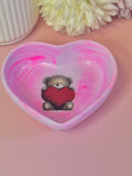 Heart-shaped trinket dish with a teddy bear holding a heart on a pink background