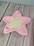 Pink star-shaped trinket dish with a yellow center on a wooden surface