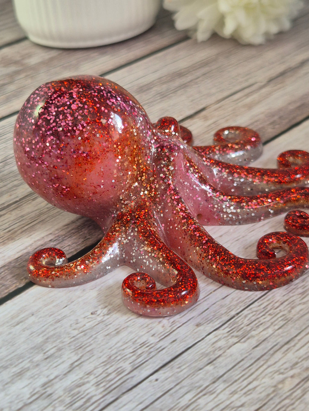 Red pink handmade resin octopus on a wooden surface side view