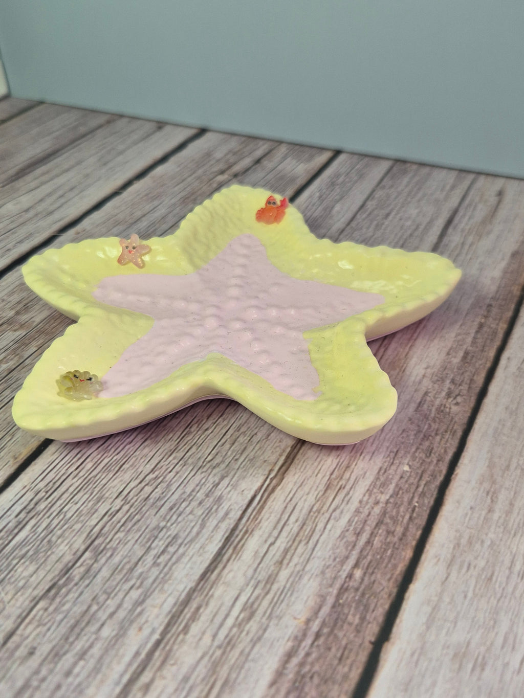 Star-shaped resincrete starfish trinket dish with a pink center on a wooden surface