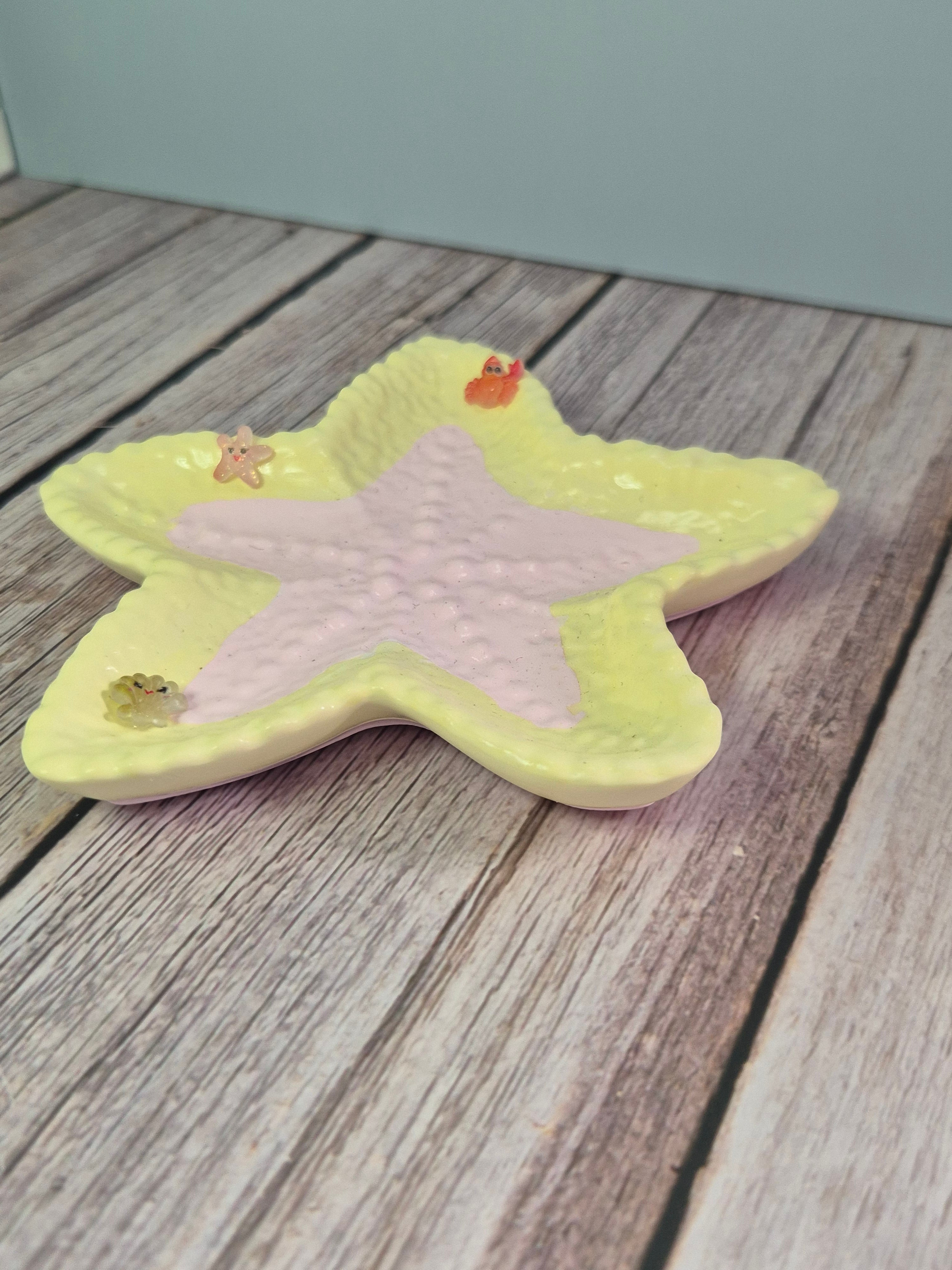 Star-shaped resincrete starfish trinket dish with a pink center on a wooden surface