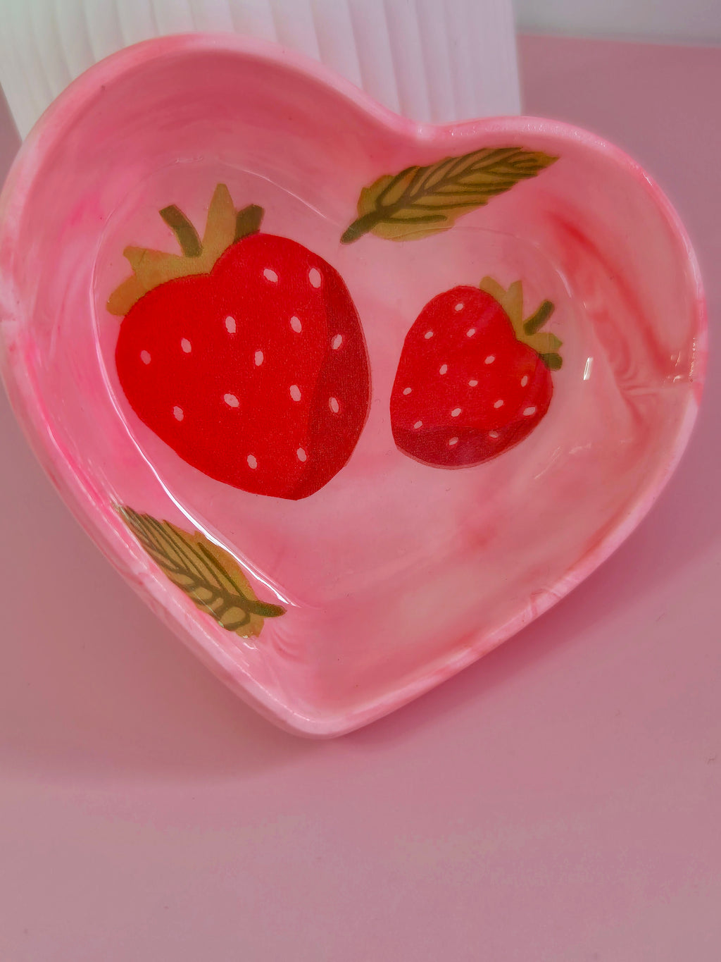 Pink handmade heart trinket dish with red strawberry, green leaf accents and a soft swirled finish for jewellery and keepsakes.