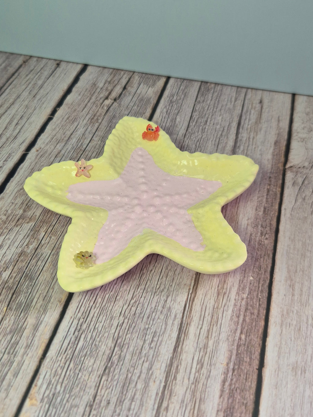 Star-shaped resincrete trinket dish on a textured surface on a wooden surface