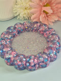 Handmade circular resin trinket tray with a raised bubble border with teal, pink beads and a glitter centre