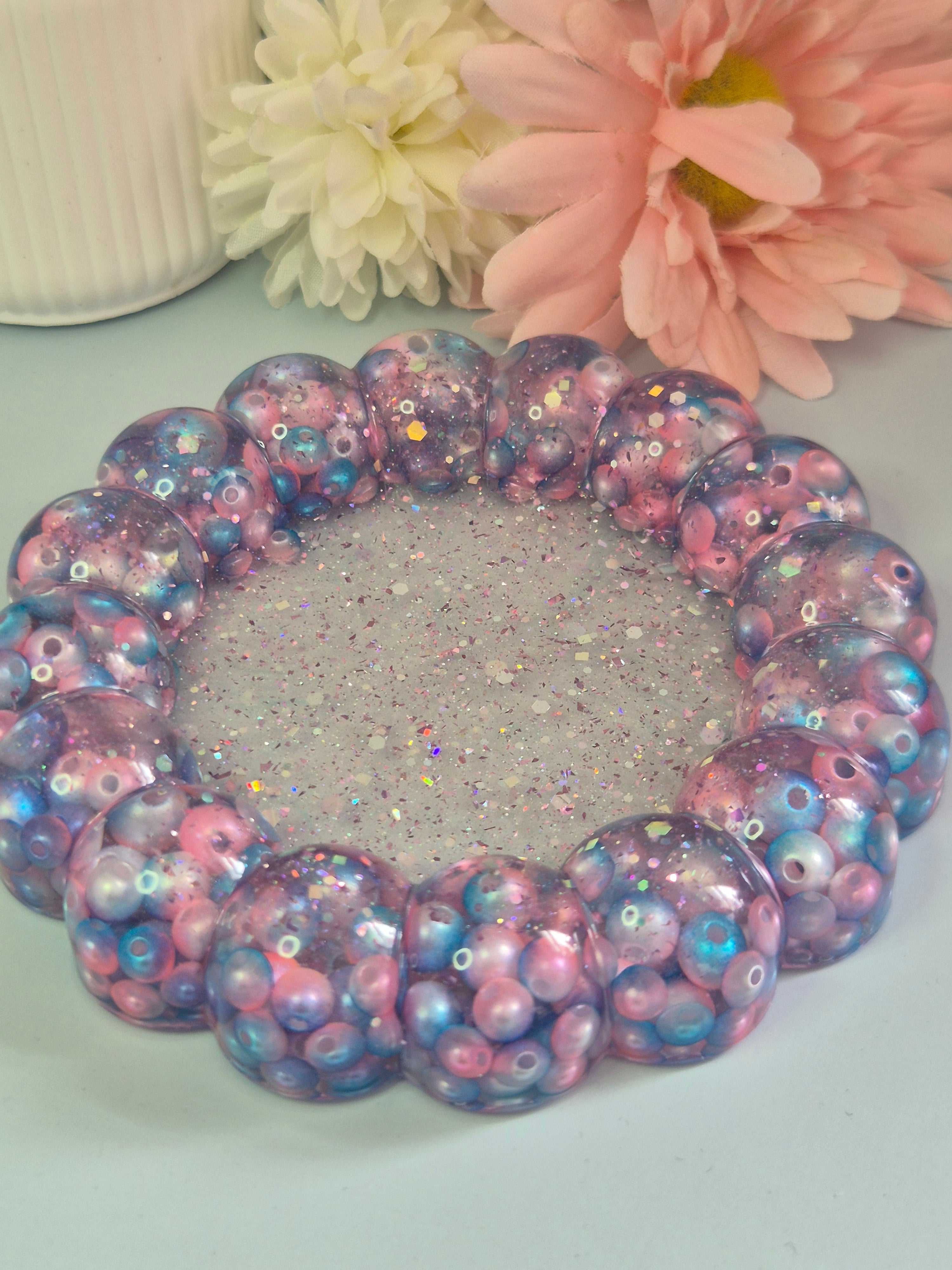 Handmade circular resin trinket tray with a raised bubble border with teal, pink beads and a glitter centre
