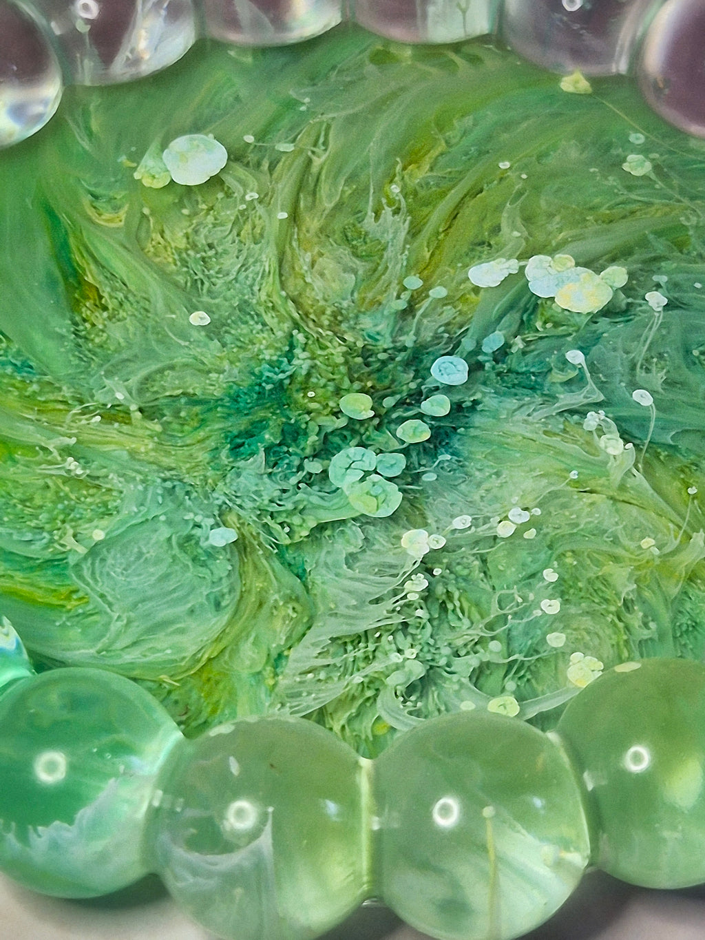Close up green resin trinket tray with flowing ink patterns throughout 